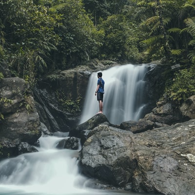 男人站在岩石和瀑布背景
